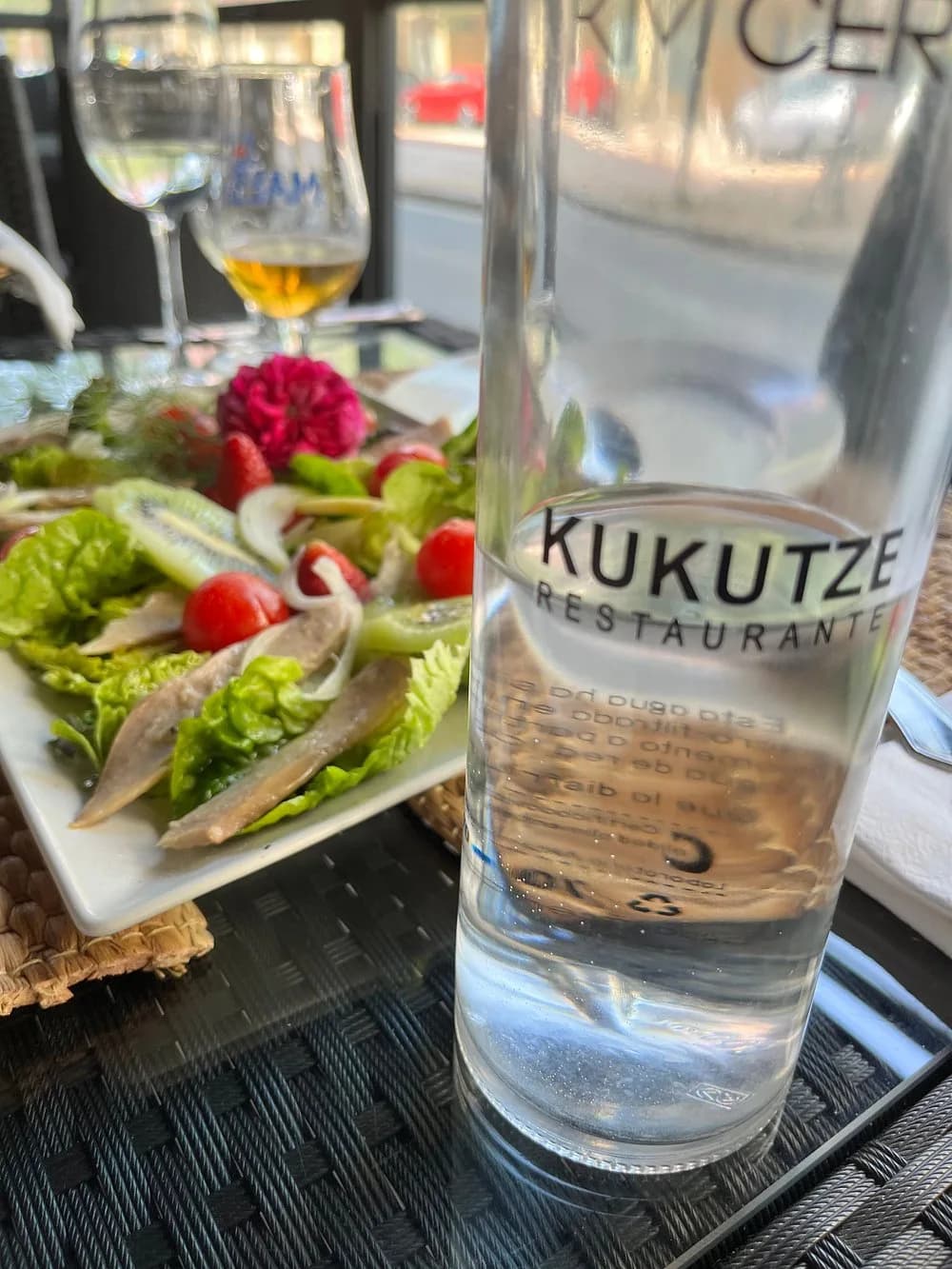 Ensalada y botella de agua Kukutze en la terraza