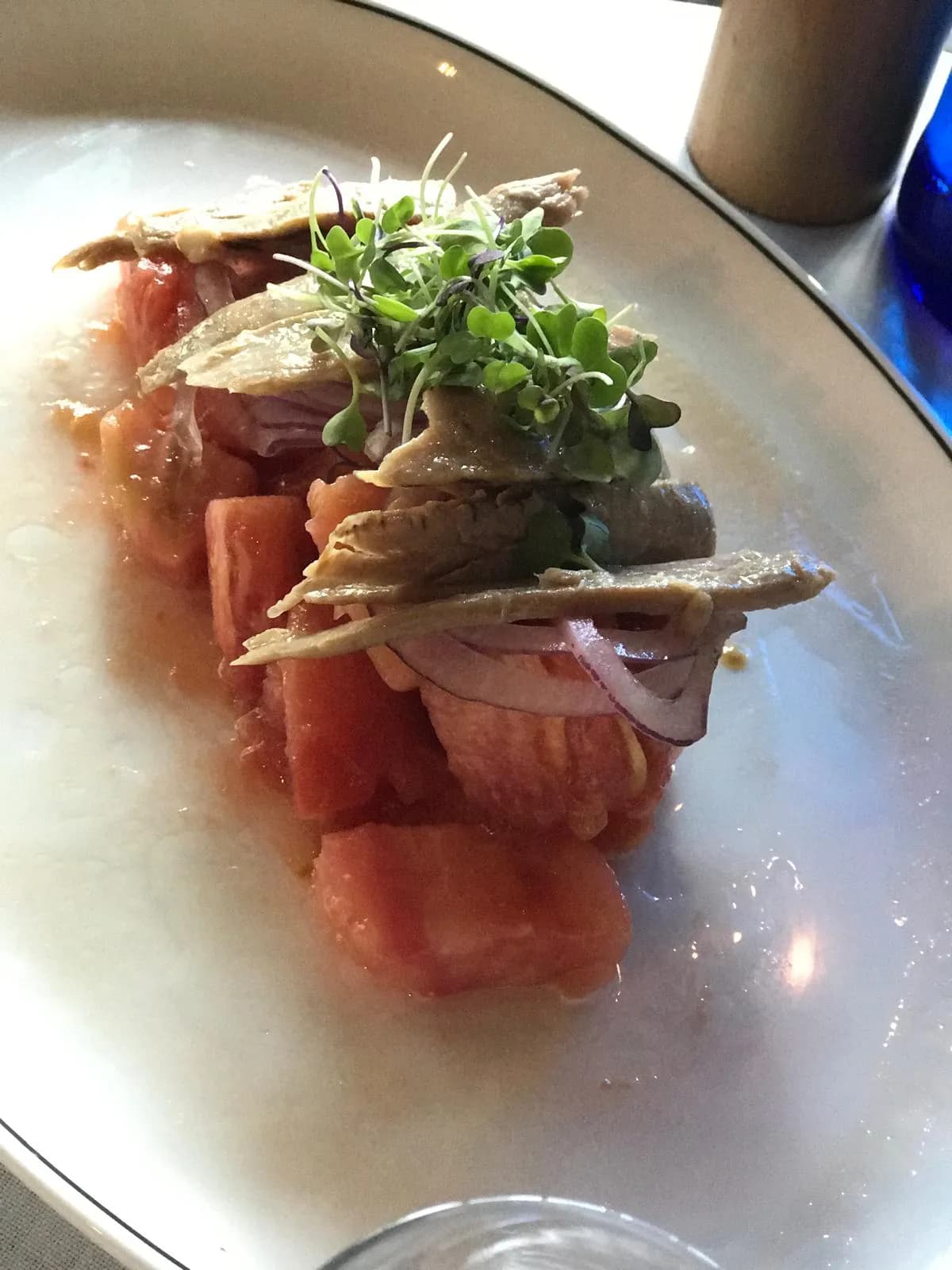 Tomate con lomos de pescado, cebolla morada y brotes